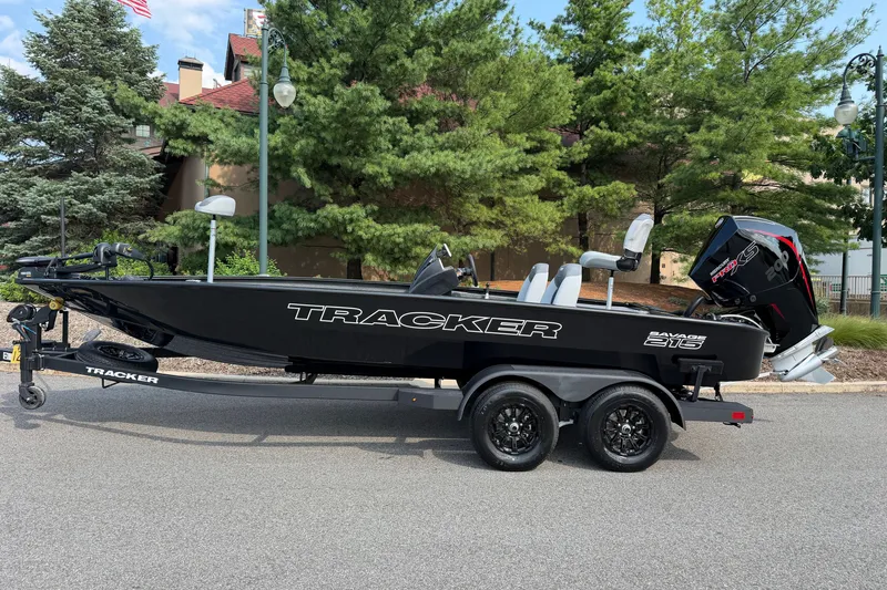The Image of 2027 Tracker Savage 215 boat on trailer, parked outdoors with trees in background. - 0
