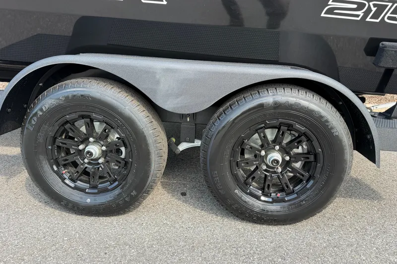 Slide: The Image of Dual black wheels on a 2027 Tracker Savage 215 trailer, featuring Load Star tires. - 51