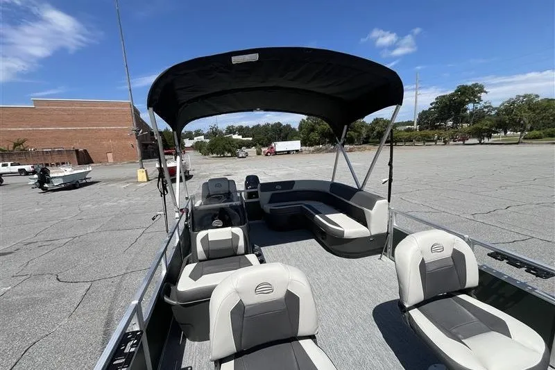 Slide: The Image of 2027 Sun Tracker Bass Buggy 16 XL Select pontoon boat with canopy in parking lot. - 13