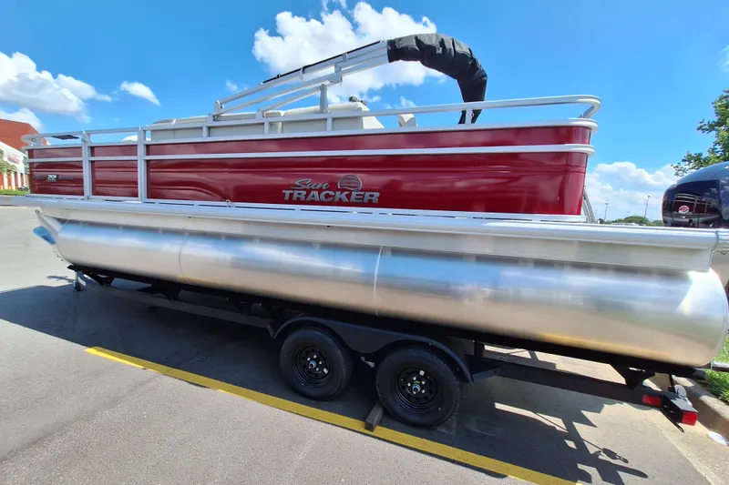 The Image of 2027 Sun Tracker Fishin' Barge 22 XP3 pontoon boat on trailer, sunny day. - 0
