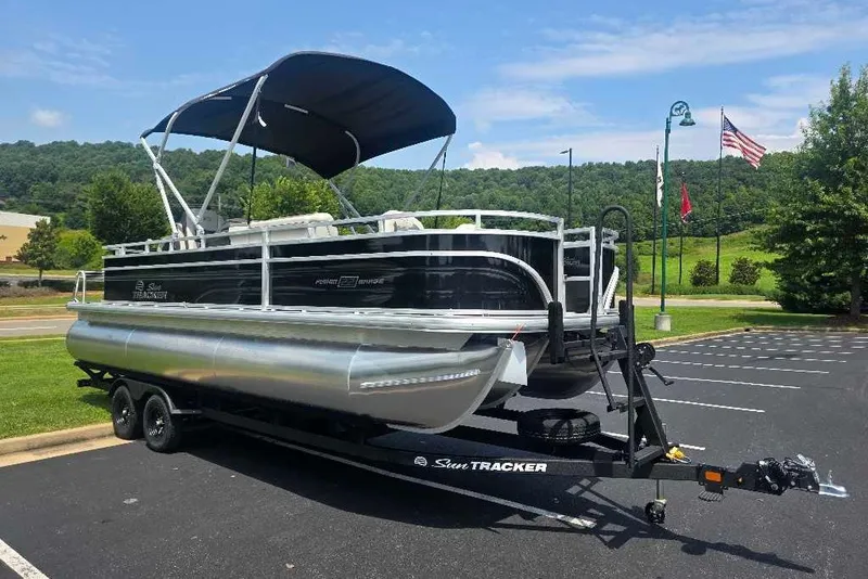 The Image of 2027 Sun Tracker Fishin' Barge 22 XP3 pontoon boat on trailer in parking lot. - 0