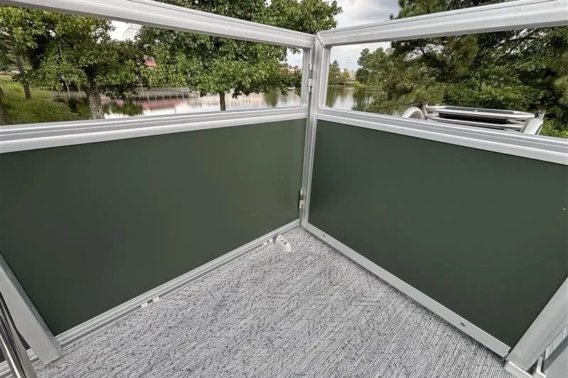 Slide: The Image of 2027 Sun Tracker Bass Buggy 18 DLX pontoon boat with green paneling and scenic lake view. - 24