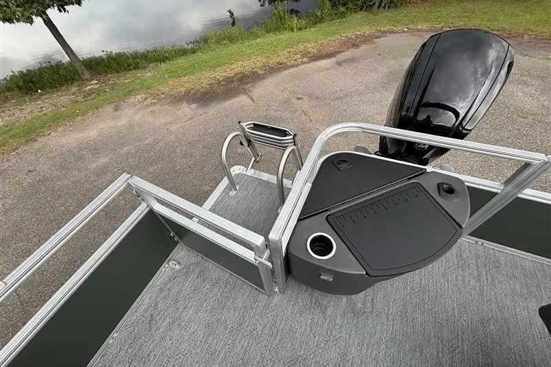 Slide: The Image of 2027 Sun Tracker Bass Buggy 18 DLX pontoon boat with motor, docked by a lake. - 25