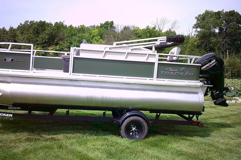 The Image of 2027 Sun Tracker Bass Buggy 18 DLX pontoon boat on trailer, parked on grass. - 0