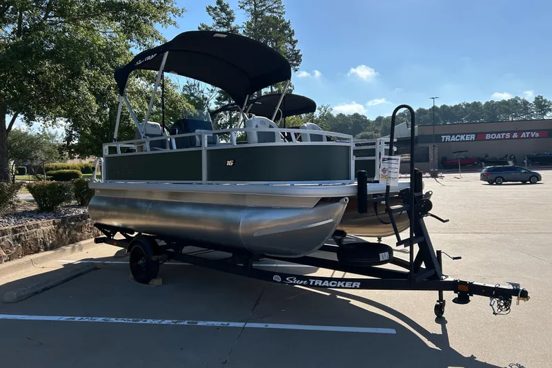 The Image of 2027 Sun Tracker Bass Buggy 16 XL Select pontoon boat on trailer in parking lot. - 0