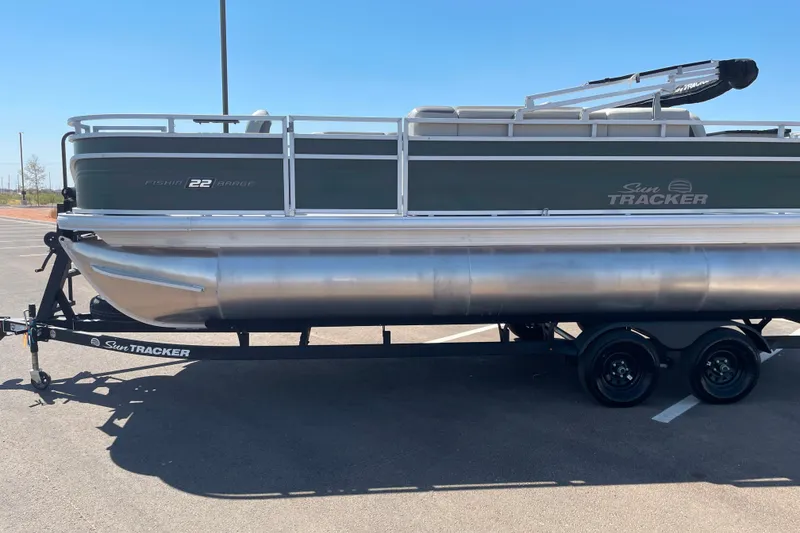 The Image of 2027 Sun Tracker Fishin' Barge 22 XP3 pontoon boat on trailer in parking lot. - 0
