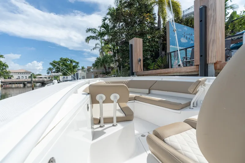 Slide: The Image of 2020 Everglades 355 Center Console boat with beige seating, docked near lush greenery. - 18