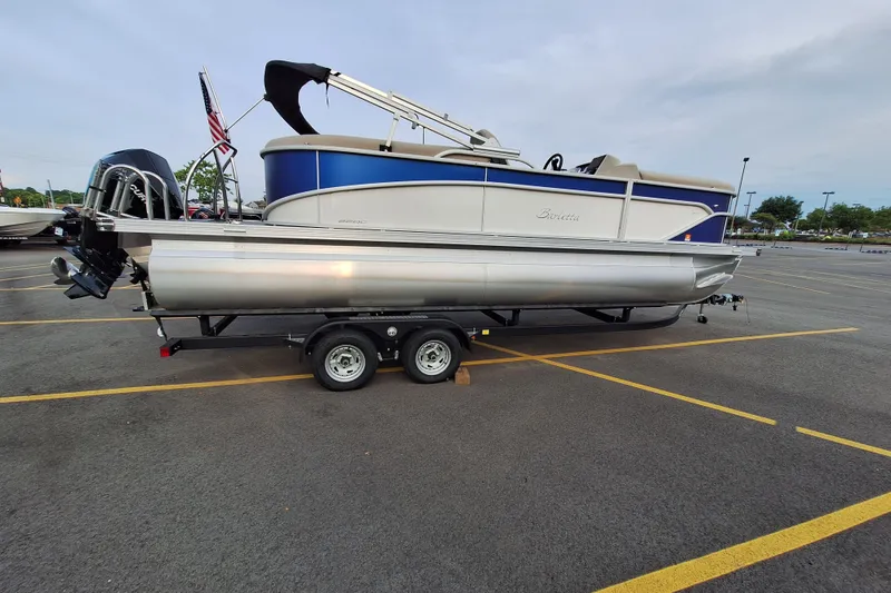 Slide: The Image of 2023 Barletta Cabrio 22QC pontoon boat on trailer in parking lot. - 2