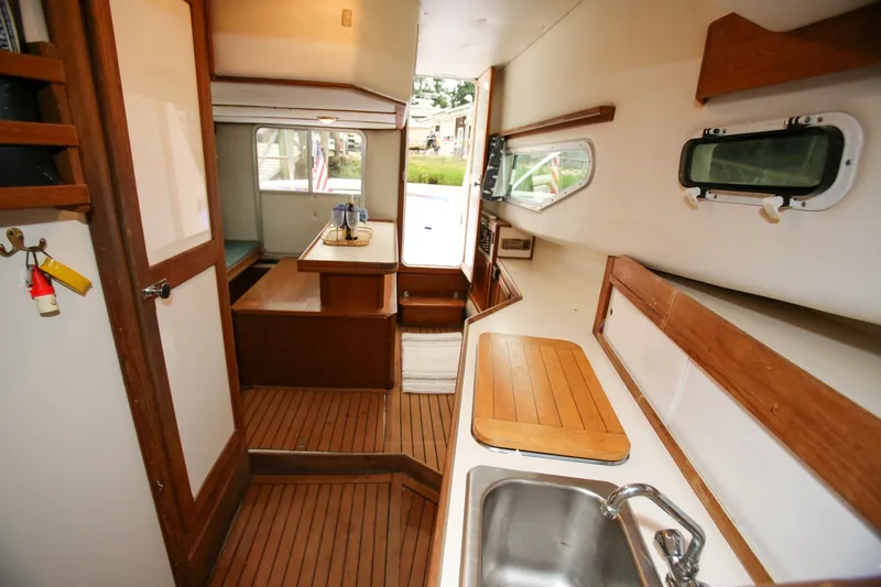 Slide: The Image of Interior of 1995 Nauset 28 Bridgedeck boat with wooden accents and compact kitchen area. - 20