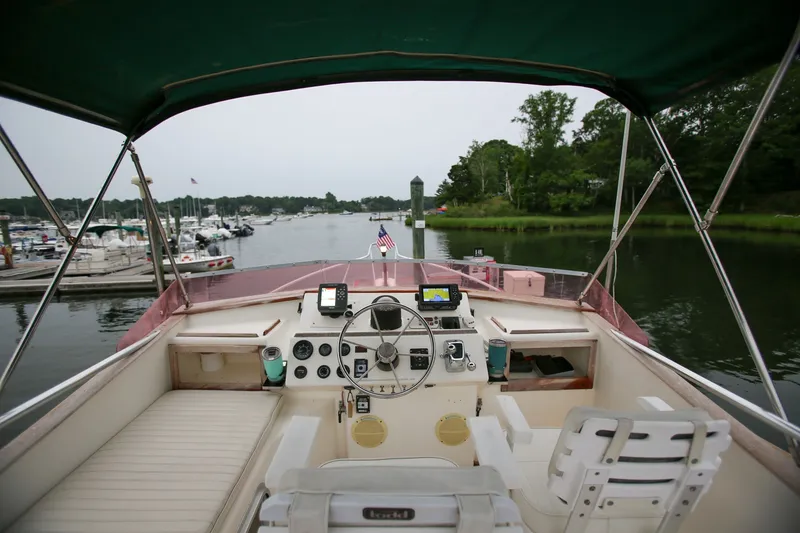 Slide: The Image of Cockpit view of 1995 Nauset 28 Bridgedeck boat navigating a serene marina. - 14