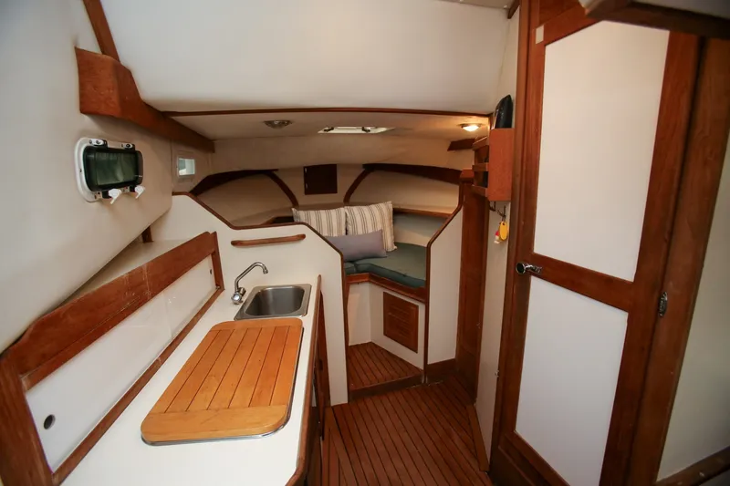 Slide: The Image of Interior of 1995 Nauset 28 Bridgedeck boat with wooden finishes and compact kitchenette. - 18