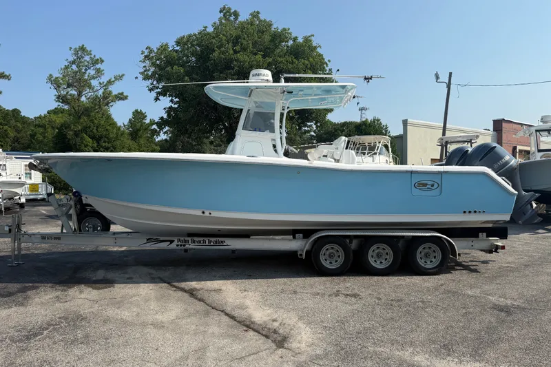 The Image of 2015 Sea Hunt Gamefish 30CB boat on trailer, light blue hull, parked outdoors. - 1
