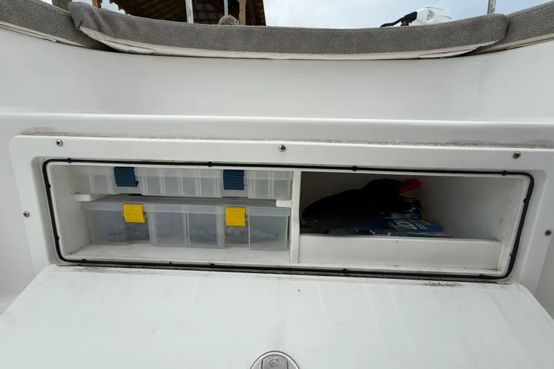 Slide: The Image of Storage compartment on a 2025 Sea Hunt BX25FS boat with organized tackle boxes. - 33