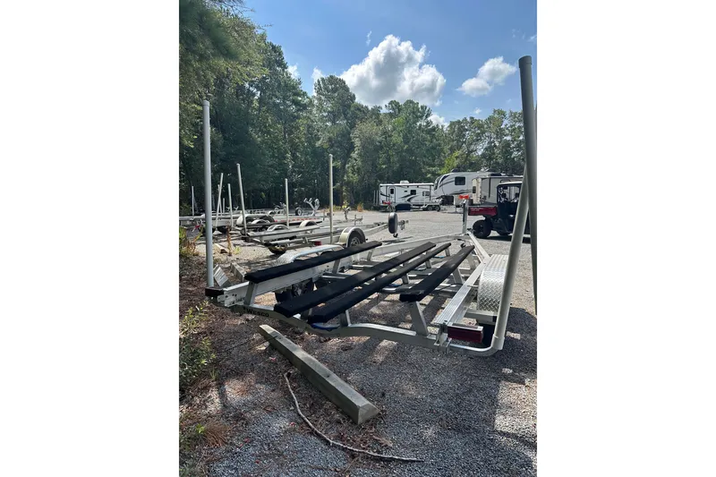 Slide: The Image of Boat trailer in a parking area, surrounded by trees and RVs, under a clear sky. - 39