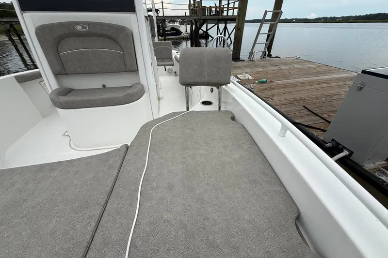 Slide: The Image of 2025 Sea Hunt BX25FS boat interior with gray seating, docked by a wooden pier. - 25