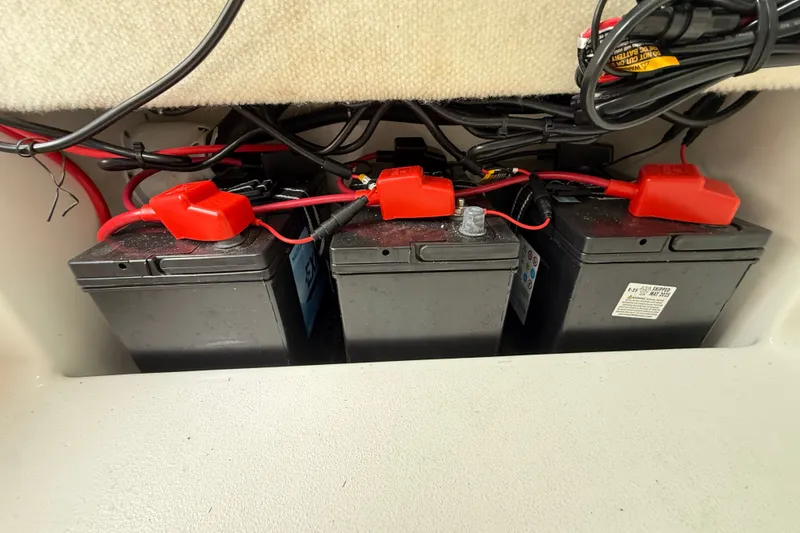 Slide: The Image of Three marine batteries with red connectors in a 2025 Sea Hunt BX25FS boat. - 36