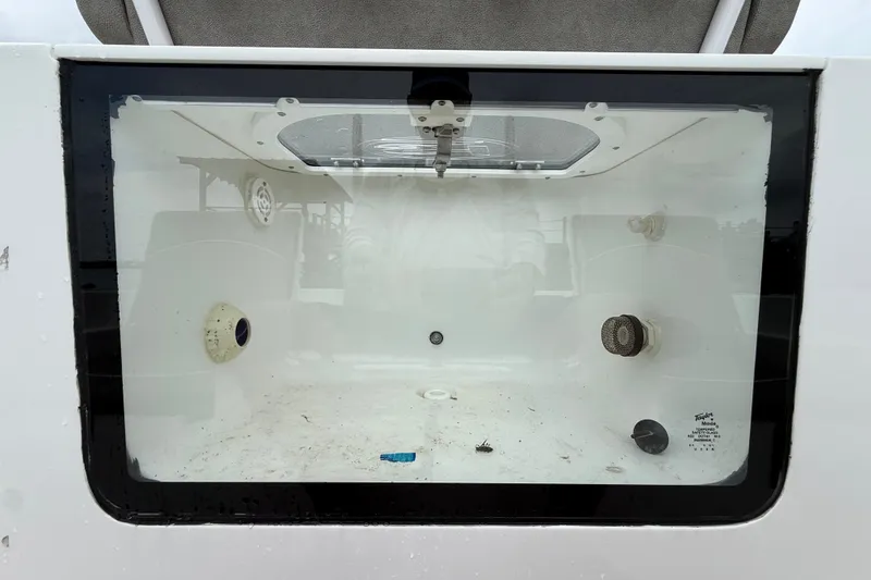 Slide: The Image of Livewell compartment of a 2025 Sea Hunt BX25FS boat, featuring clear glass and interior fittings. - 19