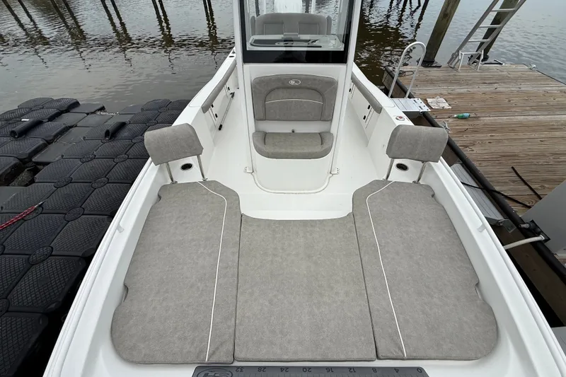 Slide: The Image of 2025 Sea Hunt BX25FS boat interior with gray seating, docked by the water. - 23