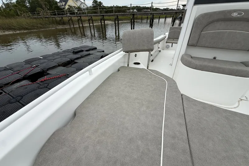 Slide: The Image of 2025 Sea Hunt BX25FS boat interior with gray seating, docked by a wooden pier. - 24