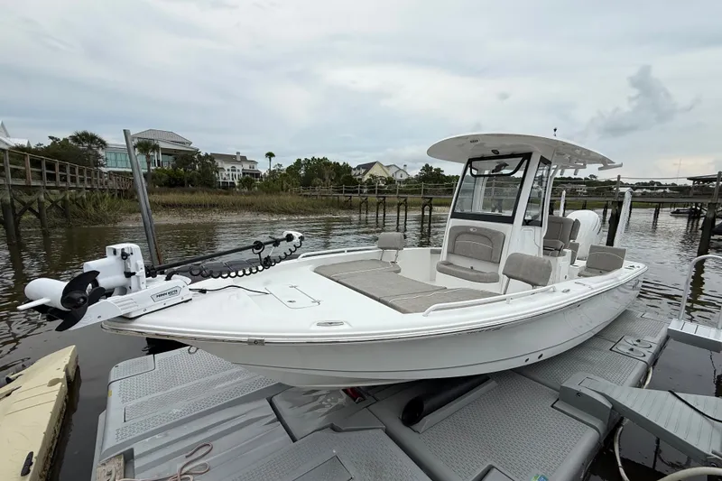Slide: The Image of 2025 Sea Hunt BX25FS boat docked on a calm waterfront with houses in the background. - 3