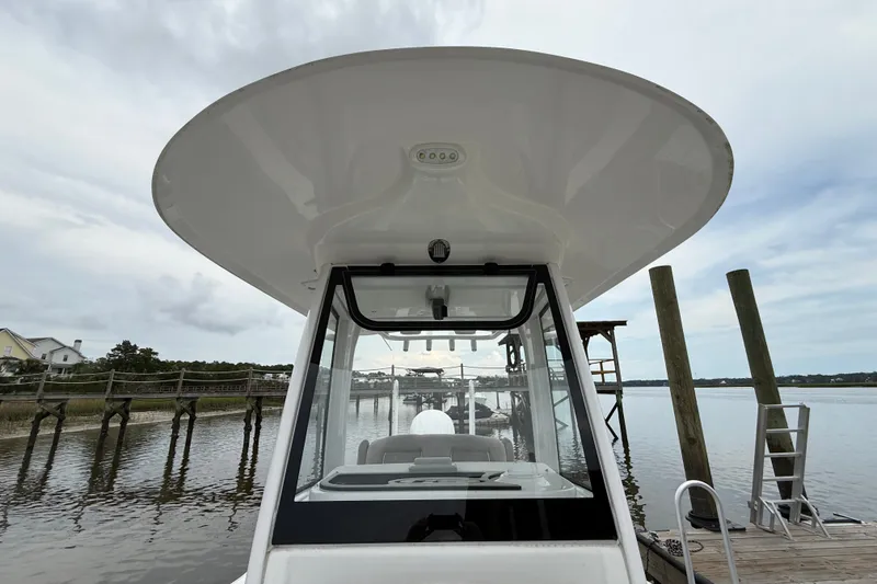 Slide: The Image of 2025 Sea Hunt BX25FS boat docked by a serene waterfront with wooden piers. - 20