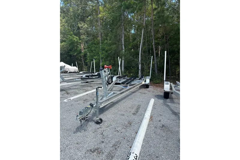 Slide: The Image of Boat trailer for 2025 Sea Hunt BX25FS on gravel lot with trees in background. - 38