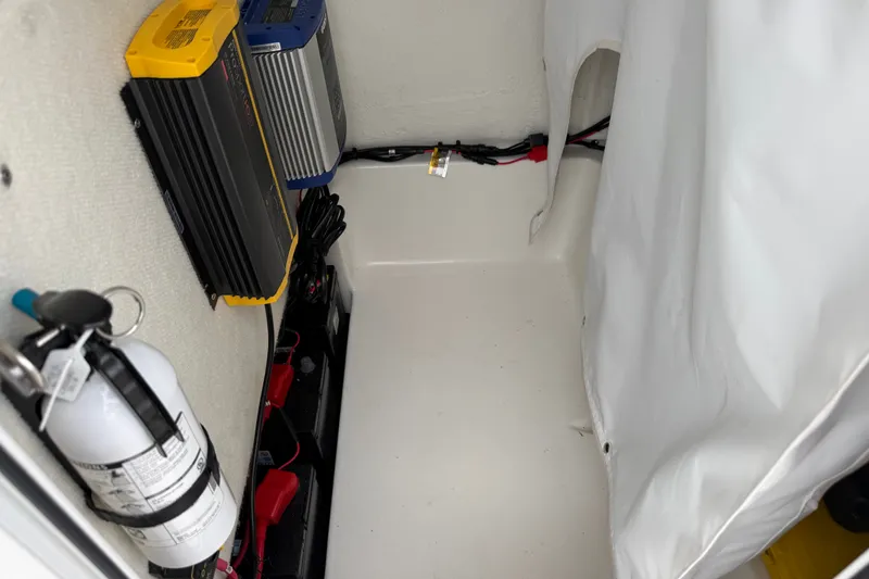 Slide: The Image of Electrical components and fire extinguisher inside a 2025 Sea Hunt BX25FS boat compartment. - 35