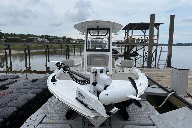 Slide: The Image of 2025 Sea Hunt BX25FS boat docked by a serene waterfront with wooden piers. - 4
