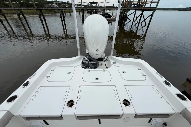 Slide: The Image of 2025 Sea Hunt BX25FS boat stern view with storage compartments and motor, docked by a wooden pier. - 27