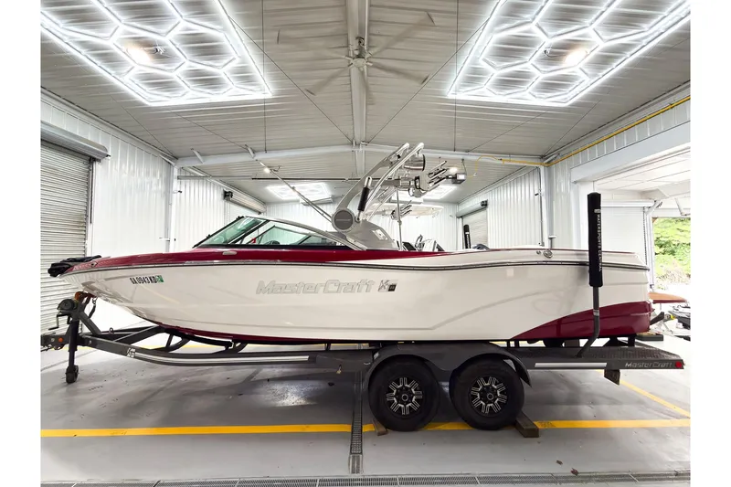 The Image of 2018 MasterCraft XT25 boat on trailer in a well-lit garage. - 0