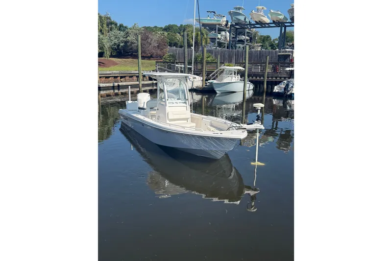 Slide: The Image of 2020 Everglades 243 Center Console boat docked in a marina, reflecting on calm water. - 2