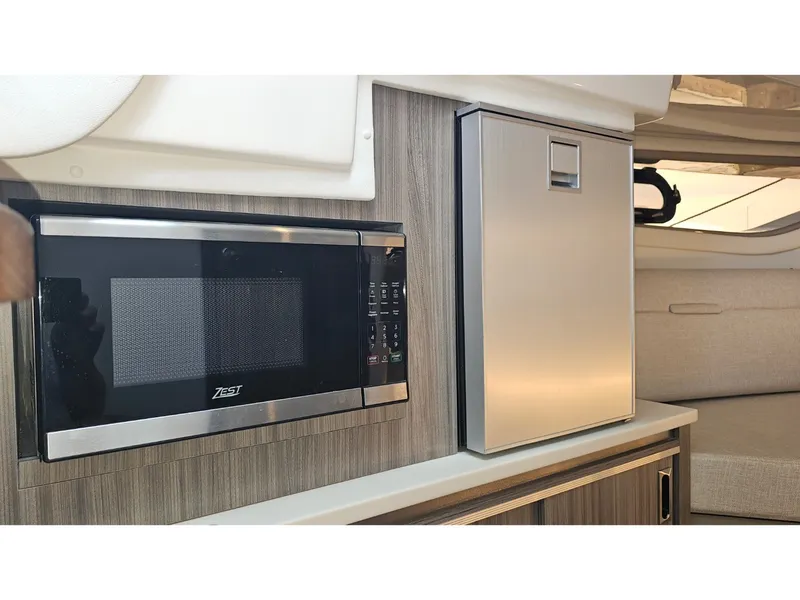 Slide: The Image of The 2026 Sea Ray Sundancer 320 Coupe Outboard features a microwave and refrigerator in its galley. - 17