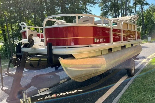Slide: The Image of 2021 Sun Tracker Bass Buggy 18 DLX pontoon boat on trailer in sunny outdoor setting. - 20