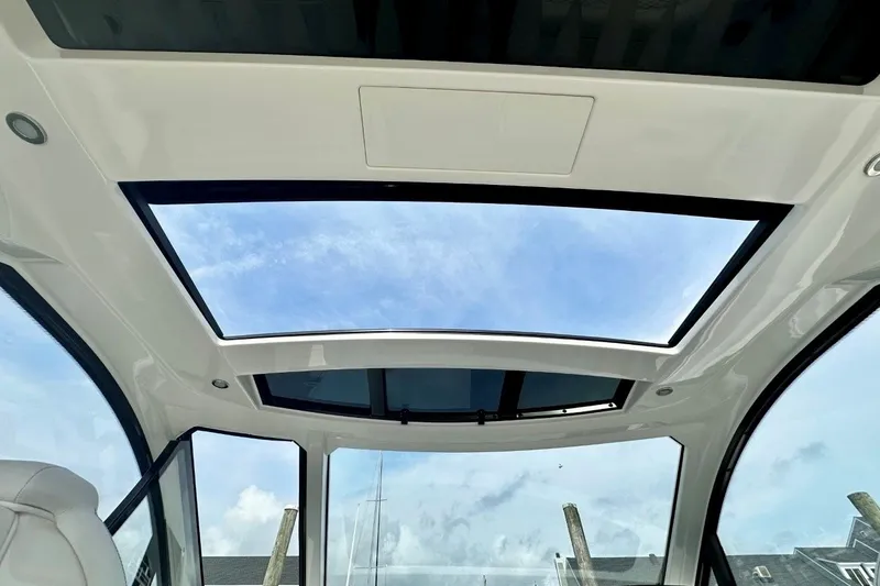 Slide: The Image of 2022 Sea Ray Sundancer 370 Outboard with panoramic sunroof and clear blue sky view. - 11