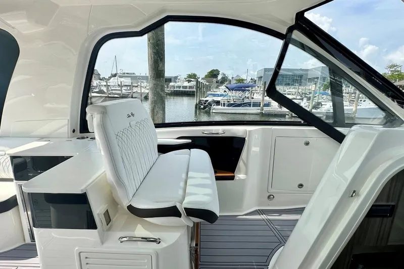 Slide: The Image of Interior view of 2022 Sea Ray Sundancer 370 Outboard, showcasing sleek seating and marina backdrop. - 13