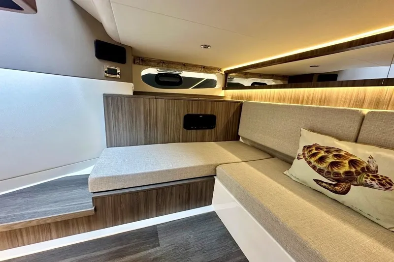 Slide: The Image of 2022 Sea Ray Sundancer 370 Outboard cabin interior with modern seating and turtle-themed pillow. - 22