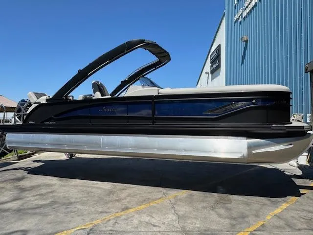 The Image of 2025 Barletta CORSA 25MA pontoon boat displayed outdoors near a blue building. - 0