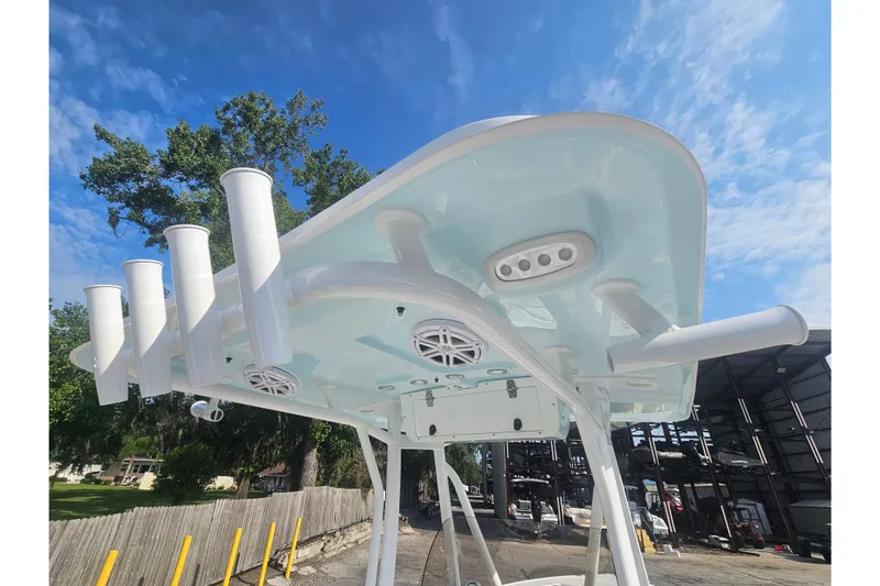 Slide: The Image of T-top of 2027 Sea Hunt Ultra 219 boat with rod holders and speakers against blue sky. - 35