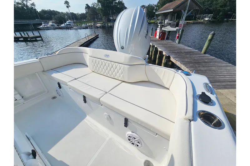 Slide: The Image of 2027 Sea Hunt Ultra 219 boat interior with cushioned seating at a dockside location. - 14