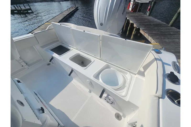 Slide: The Image of 2027 Sea Hunt Ultra 219 boat interior with open storage compartments by the dock. - 19