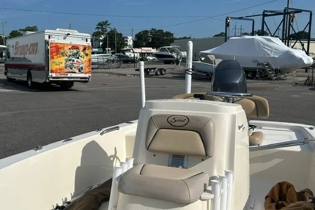 Slide: The Image of 2016 Scout 177 Sport boat in a marina with parked vehicles and boats. - 6