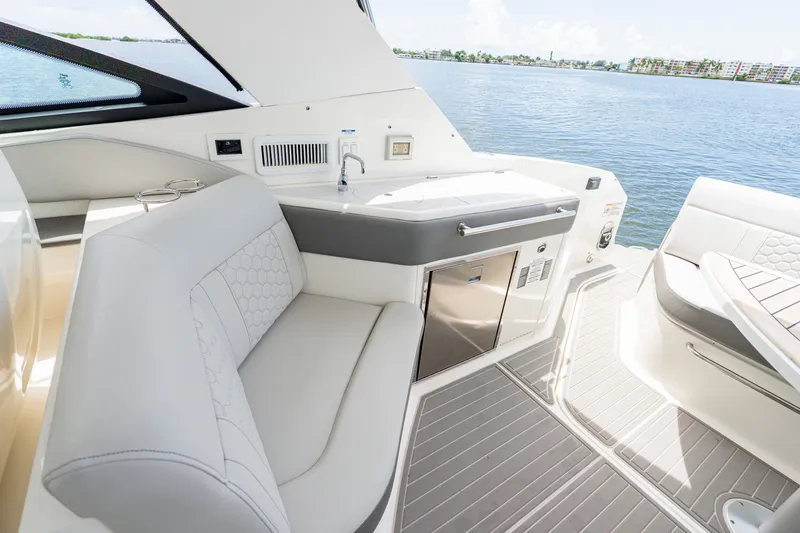 Slide: The Image of The image shows the cockpit of a 2024 Sea Ray Sundancer 320 Outboard with sleek seating and a small kitchenette. - 13
