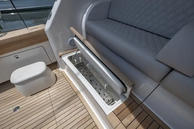 Slide: The Image of 2025 Viking 58 Convertible yacht interior with open storage compartment and cushioned seating. - 31