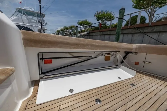 Slide: The Image of 2025 Viking 58 Convertible yacht deck with wooden flooring and storage compartment. - 32