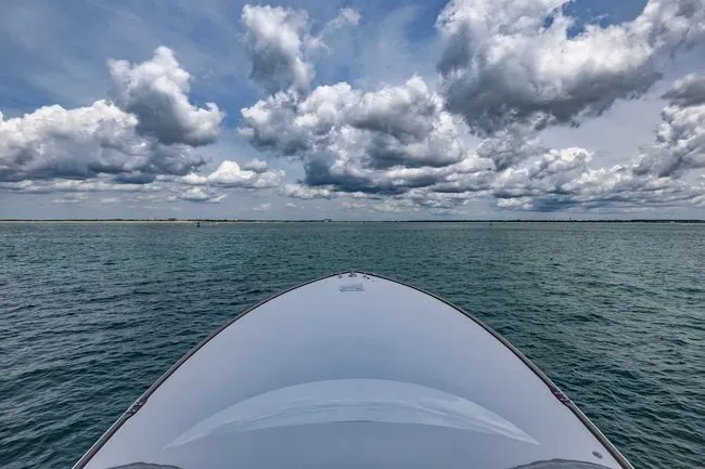 Slide: The Image of Bow of 2025 Viking 58 Convertible yacht on open sea under cloudy sky. - 14
