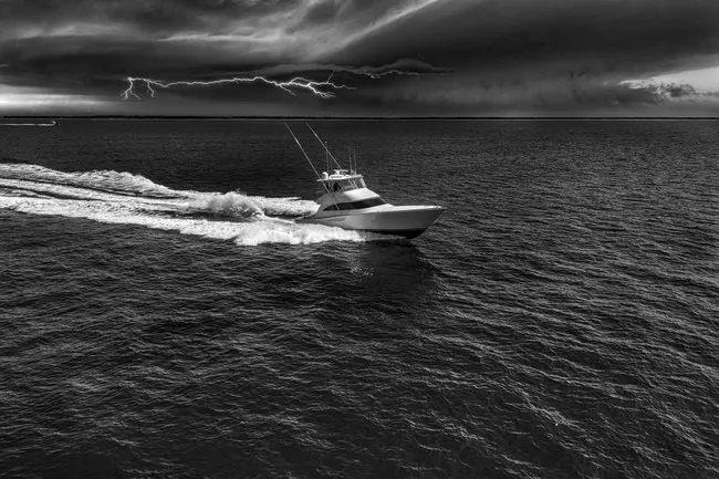 Slide: The Image of Viking 58 Convertible 2025 yacht cruising under stormy skies with lightning in the distance. - 13