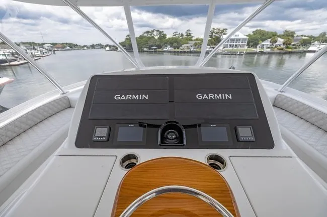 Slide: The Image of 2025 Viking 58 Convertible yacht helm with dual Garmin displays, overlooking a serene marina. - 21