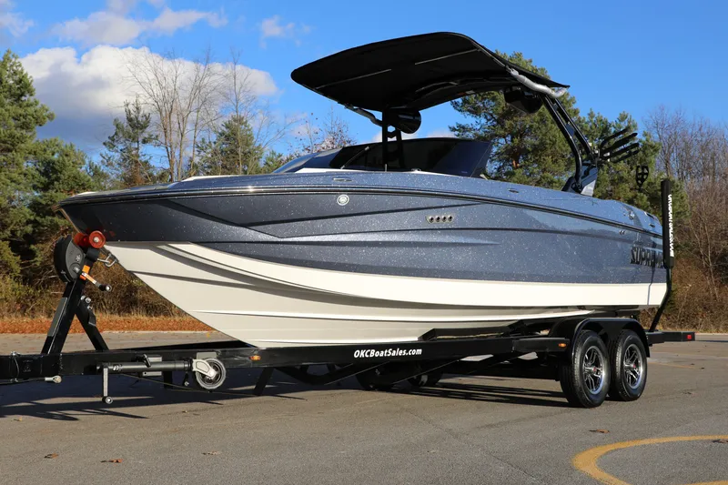 The Image of 2026 Supreme S220 boat on trailer, parked outdoors with trees in background. - 1