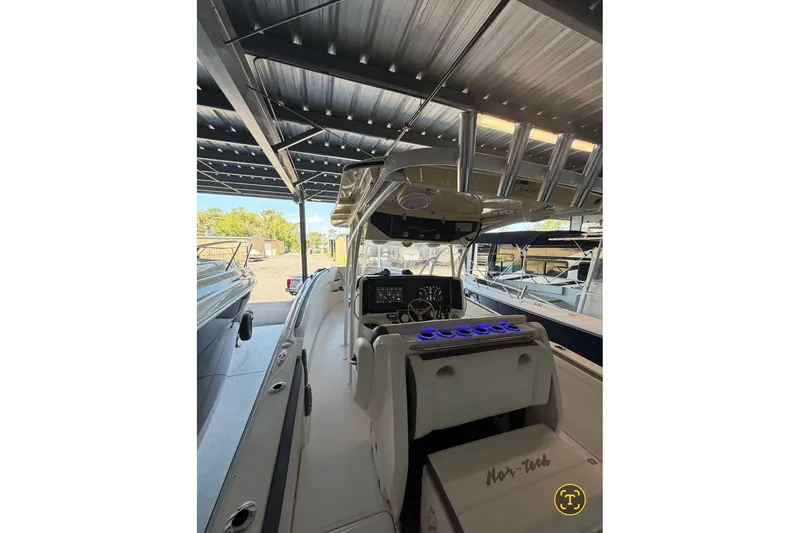 Slide: The Image of 2013 Nor-Tech 340 Sport boat interior with illuminated dashboard under a covered dock. - 14
