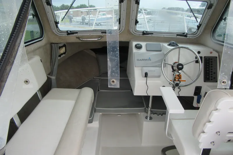 Slide: The Image of Interior of a 2016 Parker 2120 Sport Cabin boat with steering wheel and seating. - 21